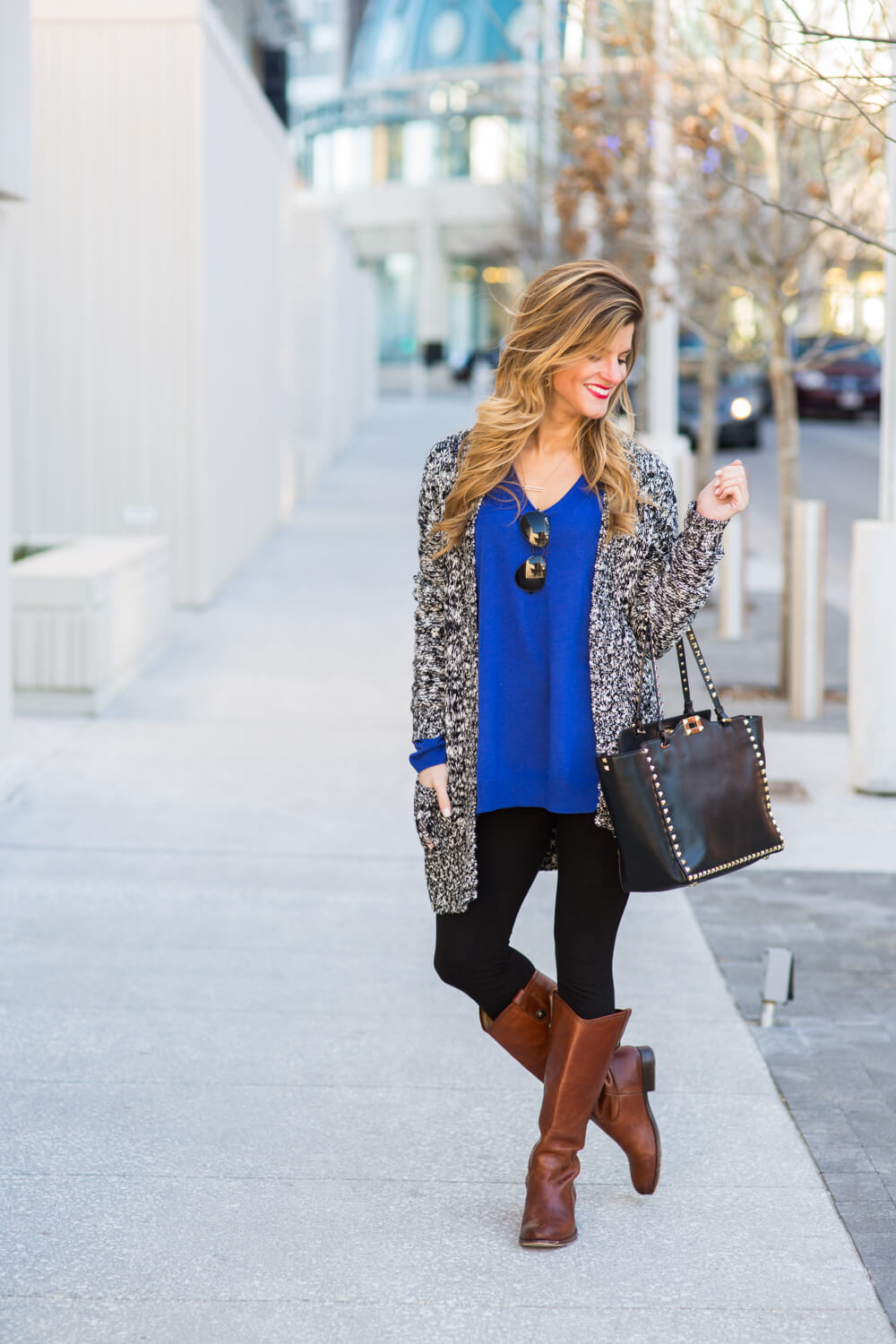 Brighton The Day wearing a long cardigan with leggings and riding boots, valentino bag, marled cardigan
