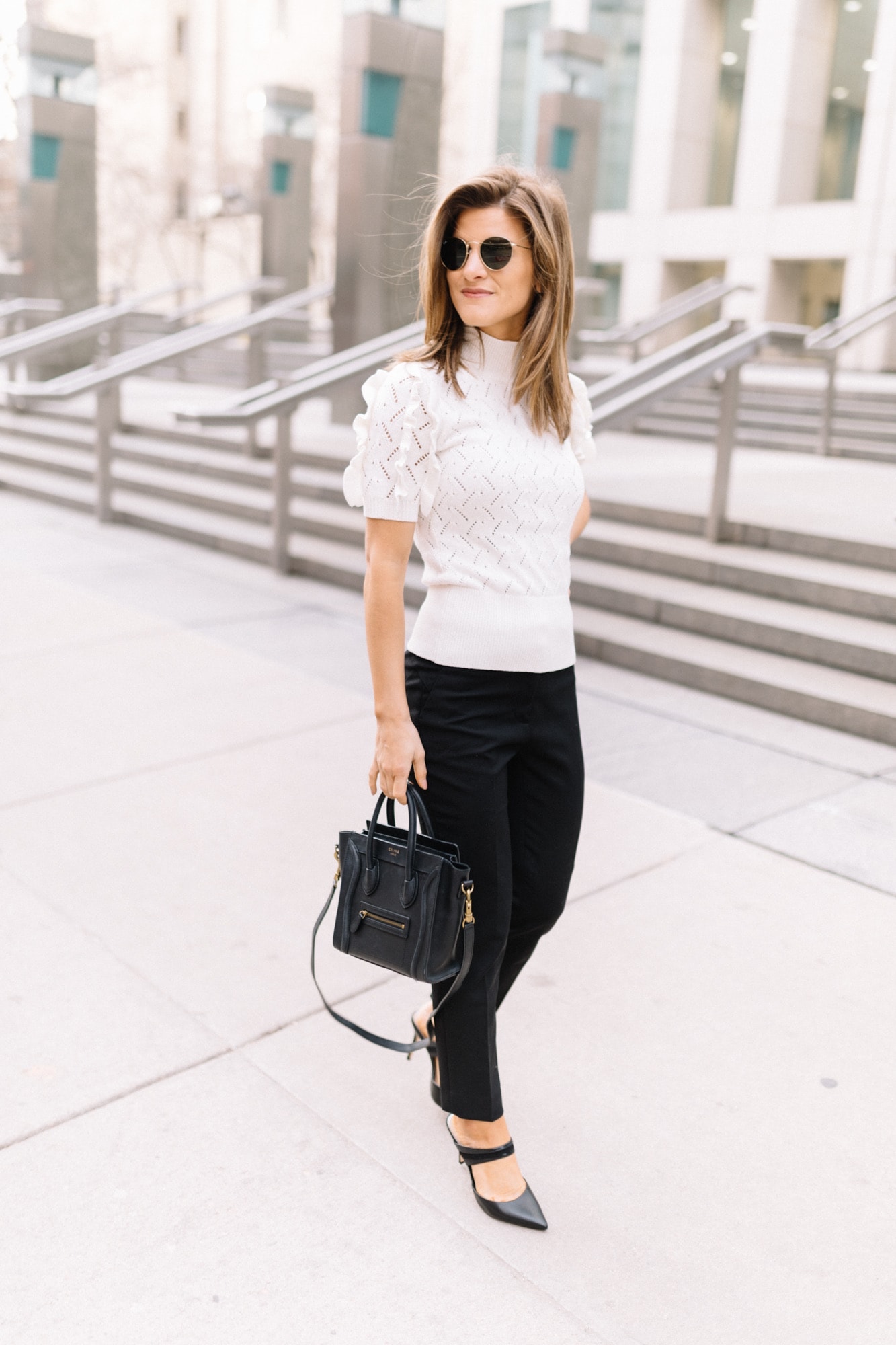 Brighton Keller wearing White House Black Market White sweater top black pants and black pumps