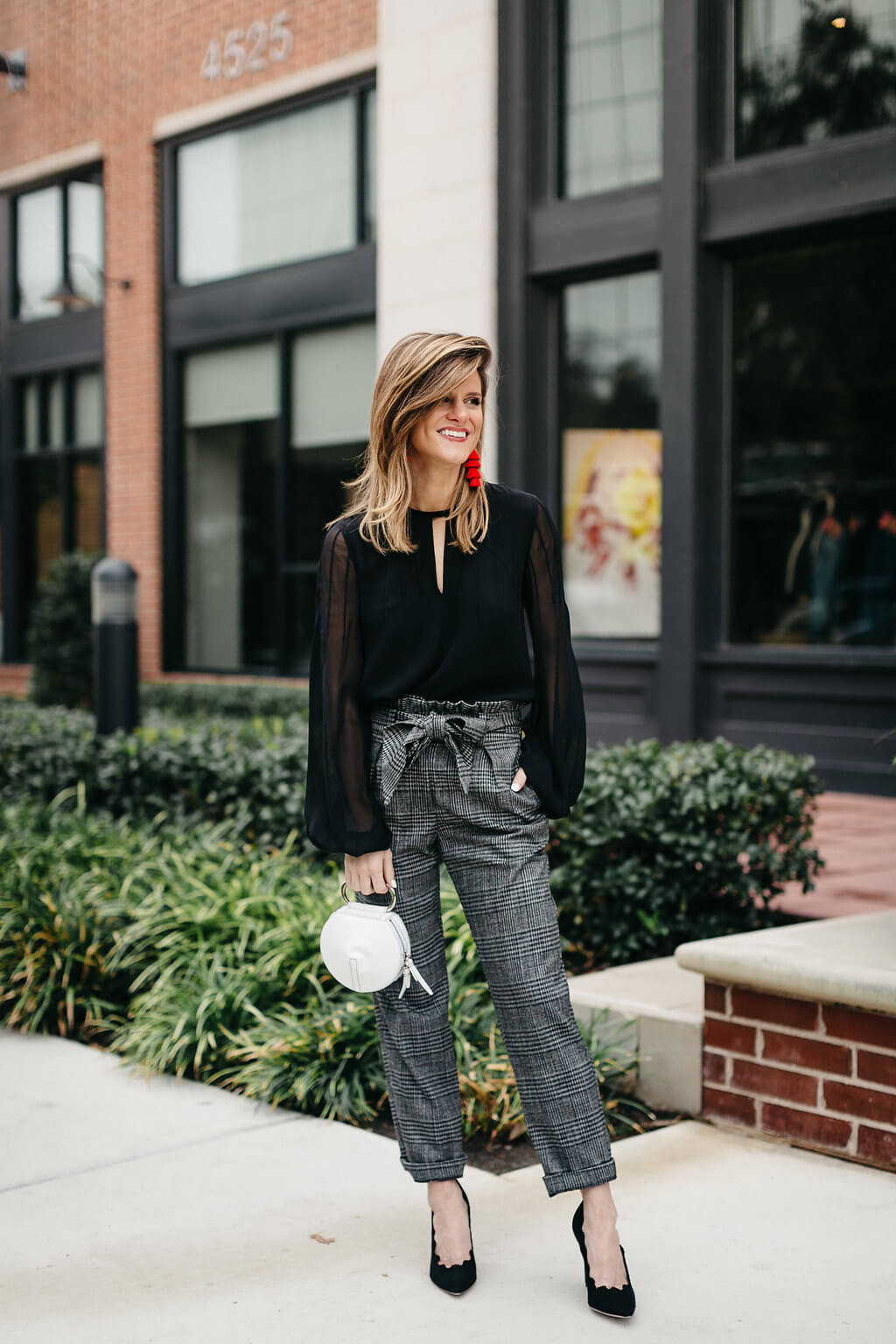 plaid trouser, black blouse, black pumps, and red tassel earrings 