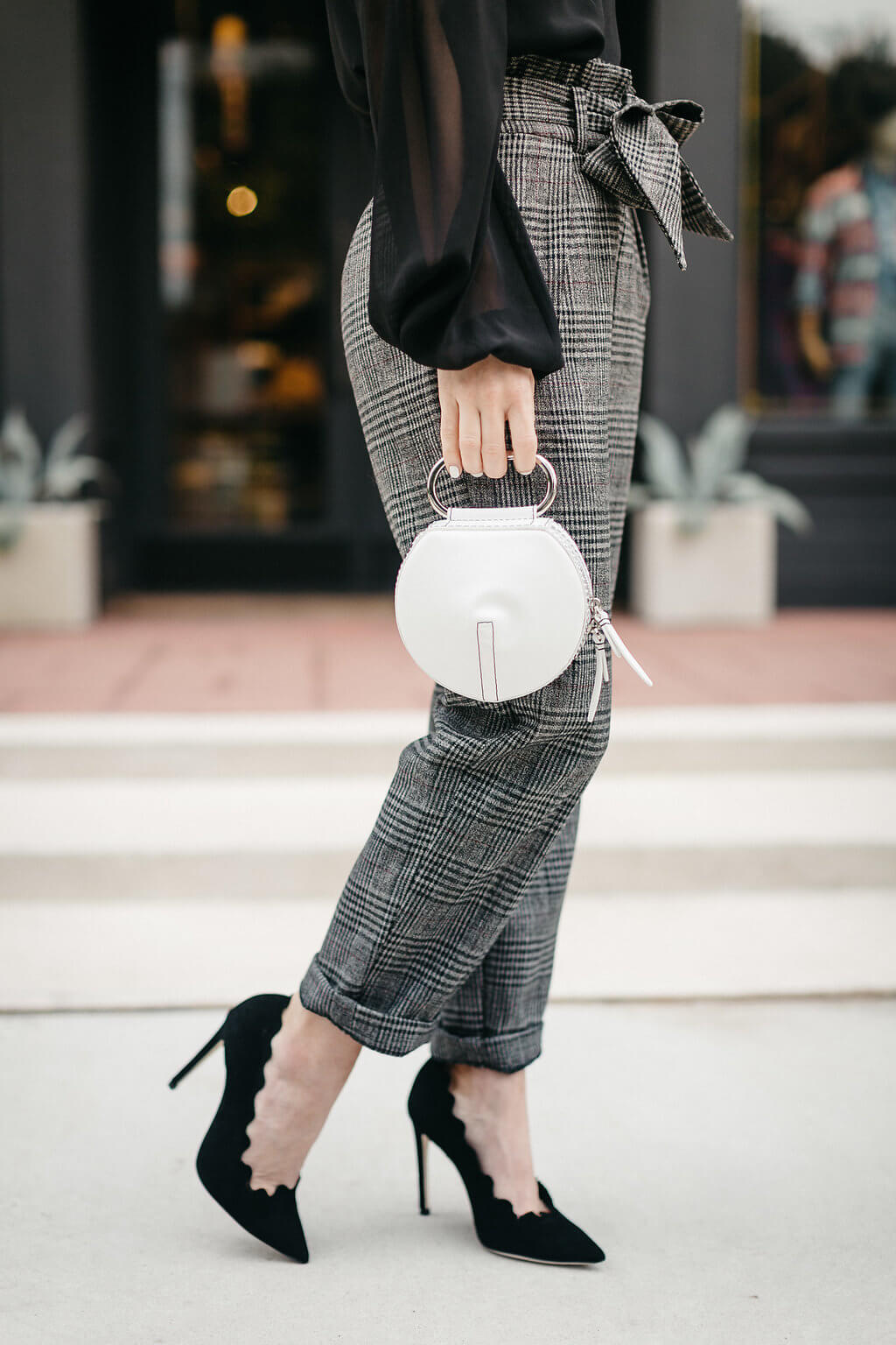 plaid trouser, black blouse, black pumps, and red tassel earrings 