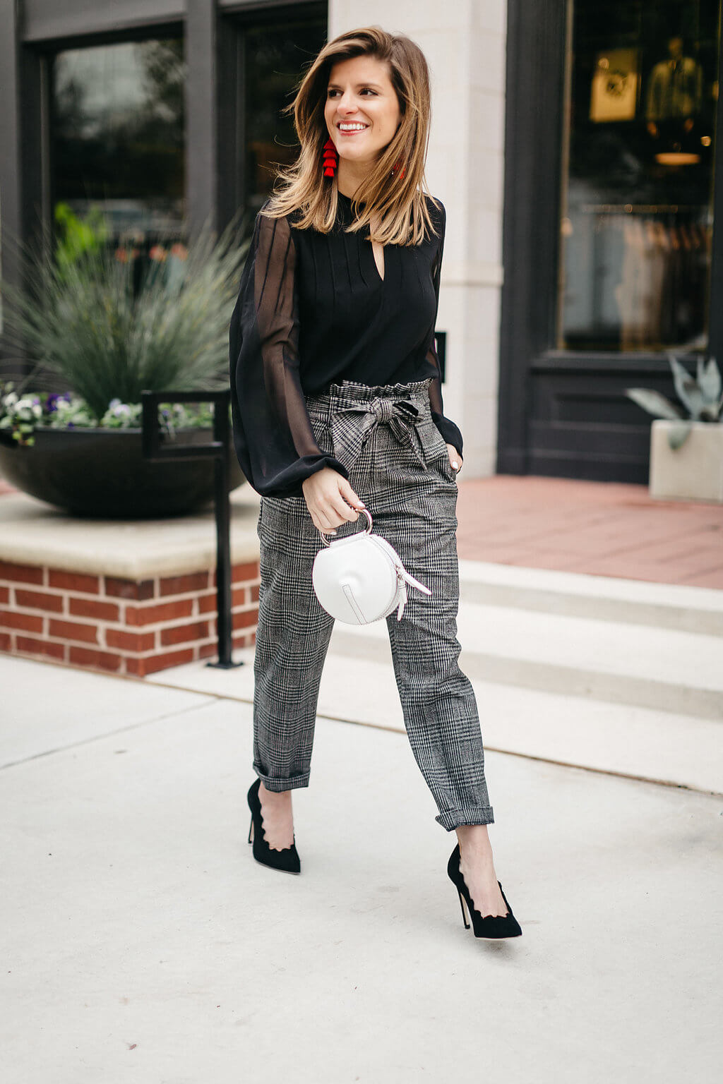 plaid trouser, black blouse, black pumps, and red tassel earrings 