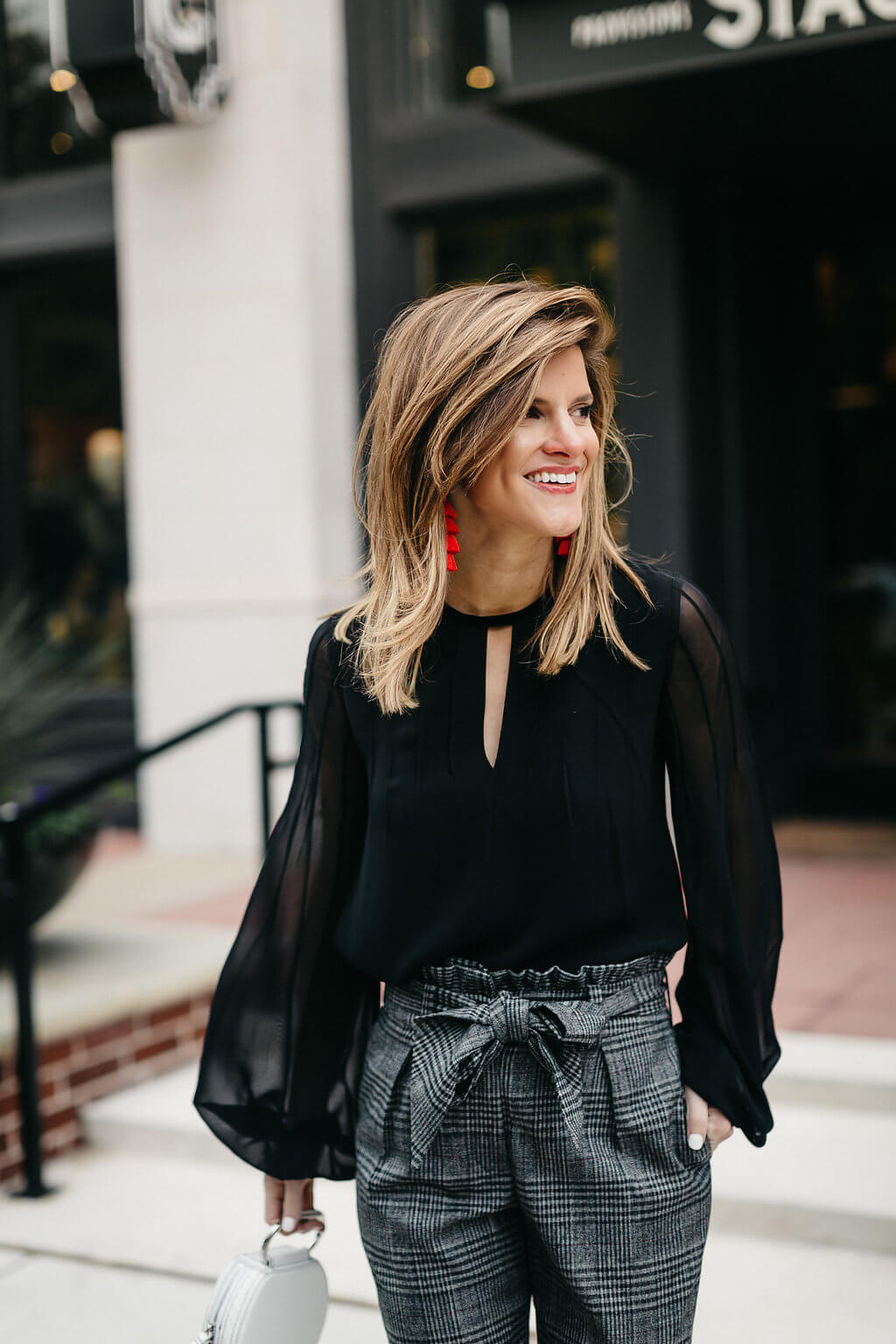 plaid trouser, black blouse, black pumps, and red tassel earrings 